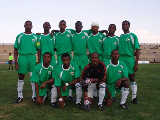 Equipe national de football des Comores en tenue verte posant sur un terrain avant un match lors des débuts en compétition internationale.